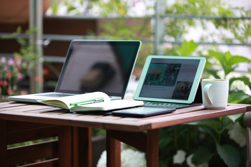 two laptops beside each other while a notebook is on top of them