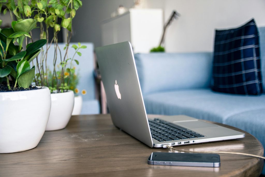 macbook and mobile phone placed on top of a wooden desk