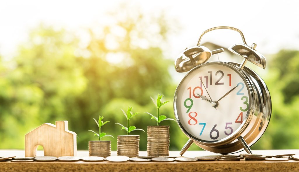 clock beside stack of growing coins